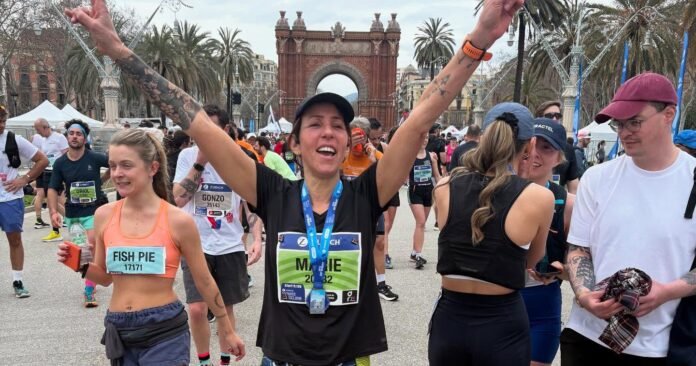 Marie célébrant son arrivée au marathon de Barcelone devant l'Arc de Triomphe avec les bras levés en signe de victoire