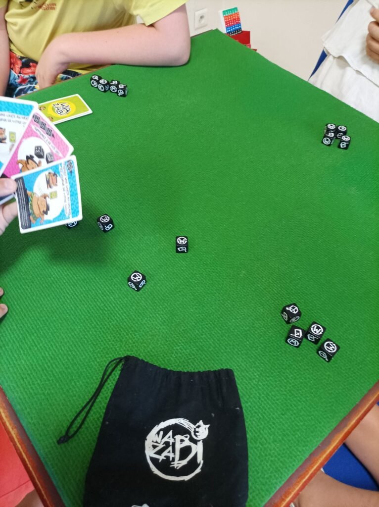 Partie de jeu Wazabi avec dés et cartes sur tapis vert, en préparation du tournoi organisé par Tartem'Pion